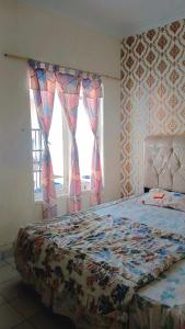 a bedroom with a bed and a window with curtains at Villa Highland No 9 Berastagi View in Berastagi