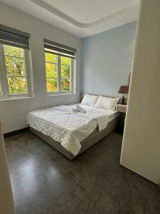 a white bedroom with a bed and two windows at Villa 04 bedrooms Novaworld Phan Thiết in Bình Sum