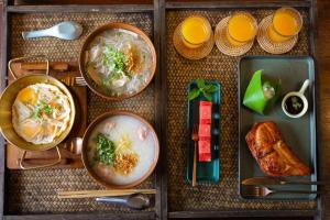 a table with three plates of food and orange juice at Suneta Hotel Chiangkhan Soi 6 in Chiang Khan