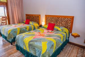 a bedroom with two beds with red pillows at Lost Iguana Resort and Spa in Fortuna