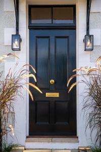 una puerta negra en una casa blanca con plantas en Luxury Historic Landmark Holdgates Cottage, en Brisbane