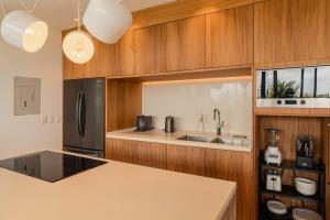 een keuken met houten kasten en een zwarte koelkast bij Galeria Privada - Tulum Hidden Masterpiece in Tulum +82 foto's