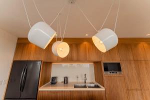 a kitchen with three lights and a refrigerator at Galeria Privada - Tulum Hidden Masterpiece in Tulum