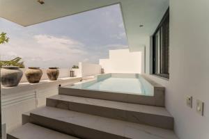 een zwembad in een huis met vazen op een richel bij Galeria Privada - Tulum Hidden Masterpiece in Tulum