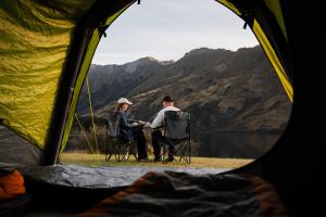 a man and woman sitting in chairs outside a tent at Rent-A-Tent - Hire camping gear in Auckland