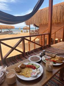a table with plates of food on the beach at Love beach camp in Taba