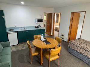 a room with a table and a kitchen and a bed at ASURE Ambassador Motor Lodge in Oamaru