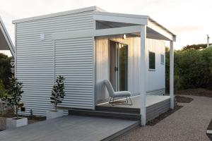 a tiny house with a chair on a deck at Island Beach Retreat in Surf Beach