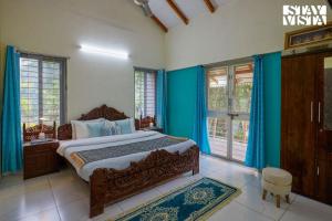 a bedroom with a bed with blue walls and windows at Whispers of Green by VEO - Part of StayVista in Trimbak