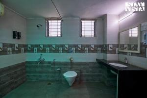 a bathroom with a toilet and a sink and a mirror at Whispers of Green by VEO - Part of StayVista in Trimbak +15 photos