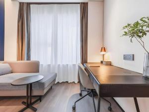 a room with a desk and a bed and a table at GreenTree Inn Shangrao Wuyishan Avenue Meide Yinxiang in Shangrao