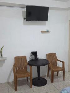 mesa con 2 sillas y TV en la pared en Yulis Home 1, en Retalhuleu
