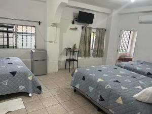 Un dormitorio con dos camas y una cocina con mesa. en Yulis Home 1, en Retalhuleu