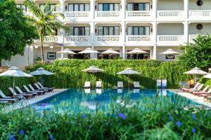 会安RiverTown Hoi An Resort & Spa的一座设有游泳池、椅子和遮阳伞的酒店