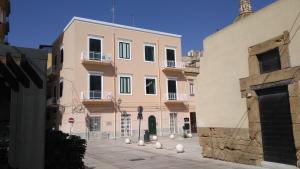 a pink building with pigeons sitting in front of it at Il Giardino Del Purgatorio in Marsala