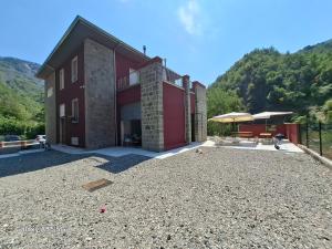 a large red building with a patio and a mountain at Rifugio Casa Cantoniera in Marsaglia