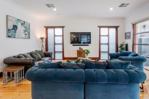a living room with two blue couches and a tv at Henley Beach House - Luxury by the Sea in Henley Beach