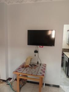 a flat screen tv hanging on a wall with a table at bayt in ‘Izbat Tall Abū Nārūz