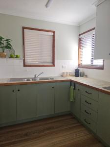 una cucina con armadi verdi e lavandino di Large Private Apartment beach sunrise park views a Urangan