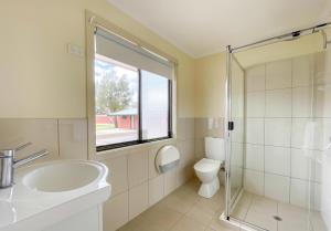 a bathroom with a sink and a toilet and a window at Tumby Bay Caravan Park in Tumby Bay