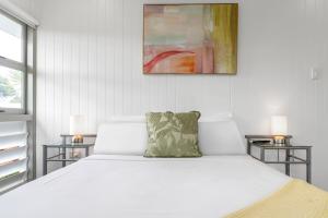 a bedroom with a large white bed with two side tables at 'Perfect Pool House' Idyllic Tropical Retreat in Edge Hill +37 photos