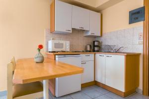 a kitchen with white cabinets and a wooden table at Pavlos Hotel in Kos Town