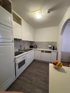 a kitchen with white cabinets and a bowl of fruit on the counter at Appartement Schneider in Sankt Anton am Arlberg +9 photos