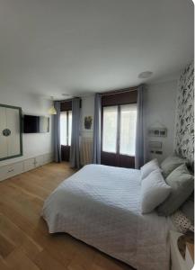 ein weißes Schlafzimmer mit einem großen Bett und einem TV in der Unterkunft Aitetxe II Laguardia in Laguardia