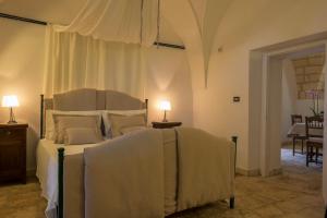 a bedroom with a bed and a table with a lamp at Masseria Pagliamonte Ortensia in San Vito dei Normanni