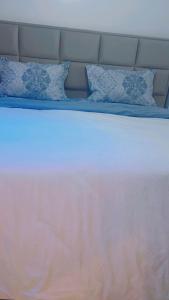 a white bed with blue pillows on top of it at Coumbis Faye in Brussels