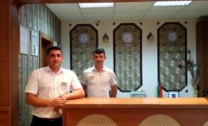 two men standing behind a desk in a room with clocks at Hotel Olymp in Sunny Beach