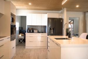 Una cocina con gabinetes blancos y un refrigerador negro. en No3onfraser, en Twizel 17 fotos más