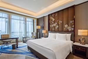 銀川市にあるWanda Realm Yinchuanの大きなベッドと机のある寝室