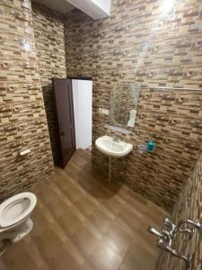 a bathroom with a white toilet and a sink at Budhibhaihomstay in Bīr