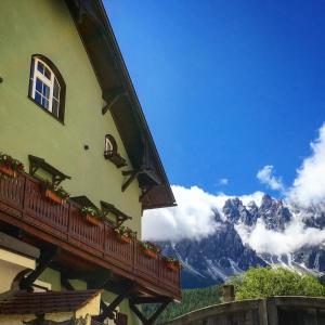 a building with a balcony with mountains in the background at Zenana Boutique Hotel in San Candido