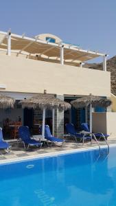a swimming pool with blue chairs and umbrellas at Lucia Villas in Perissa