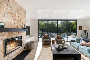 a living room with a large stone fireplace at Hiraeth - Pool Spa Beach & Village in Mount Martha