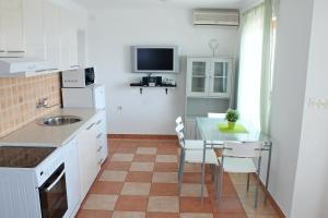 a kitchen with a table and a tv on the wall at Apartments Villa Milna 1 in Budva