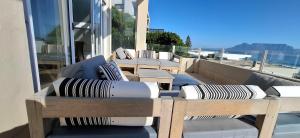 ブロウベルフストランドにある2WhiteWaters Bloubergstrand Homestayの建物の上のソファと枕が置かれたバルコニー +2枚の写真