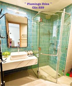 a bathroom with a sink and a shower with a mirror at Flamingo Hải Tiến IBIZA in Gò Ba Quần