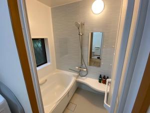 a bathroom with a tub and a shower and a sink at ゲストハウスえらぶー7 in Wadomari