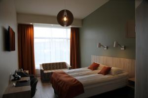 Hotel Hallormsstadur في هاتْلورمستادور: غرفة نوم بسرير وكرسي ونافذة