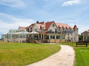 a large house on a grassy field next to a dirt road at North Shore Hotel in Skegness