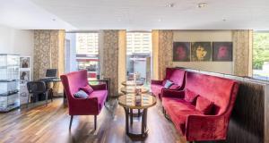 a living room with two red couches and a table at PLAZA Premium Salzburg in Salzburg