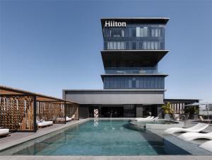 a hotel with a swimming pool in front of a building at Hilton Guadalajara Midtown in Guadalajara