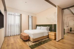 une chambre avec un lit blanc et une grande fenêtre dans l'établissement Hilton Garden Inn Olympic Sports Center Jinan, à Jinan 36 autres photos