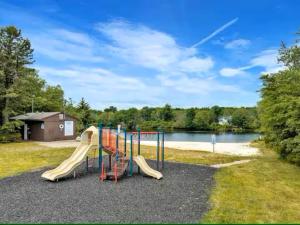 a playground with a slide next to a lake at Pocono Mountain Escape - Steps to Lake- Hot Tub - Games- 9 Mins to Ski Slopes! in Long Pond