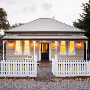 a house with a white fence in front of it at Victorian Hilltop Retreat - Firepit & Sunset Views in Castlemaine