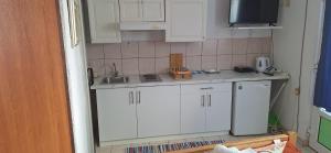 a kitchen with white cabinets and a sink and a refrigerator at Apartman's Villi in Jadranovo