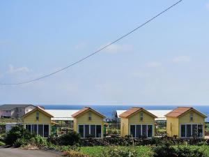 a row of yellow houses with the ocean in the background at Udo Sunflower Pension in Yŏngil-tong
